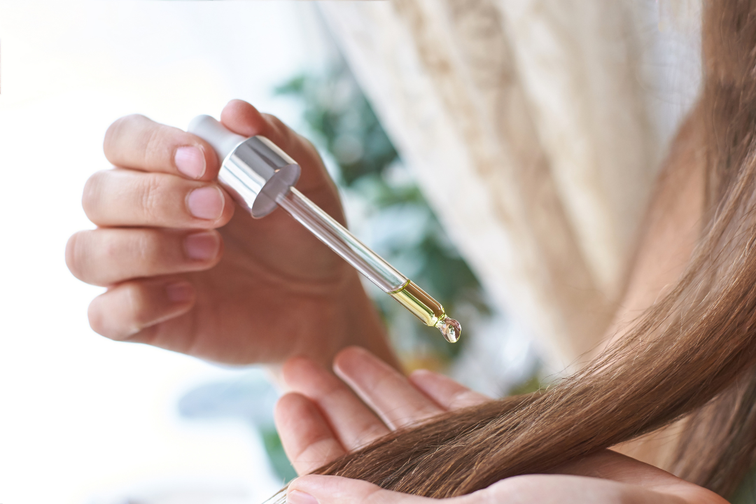 Frauen Hand, die Haaröl in die Haarspitzen tropft